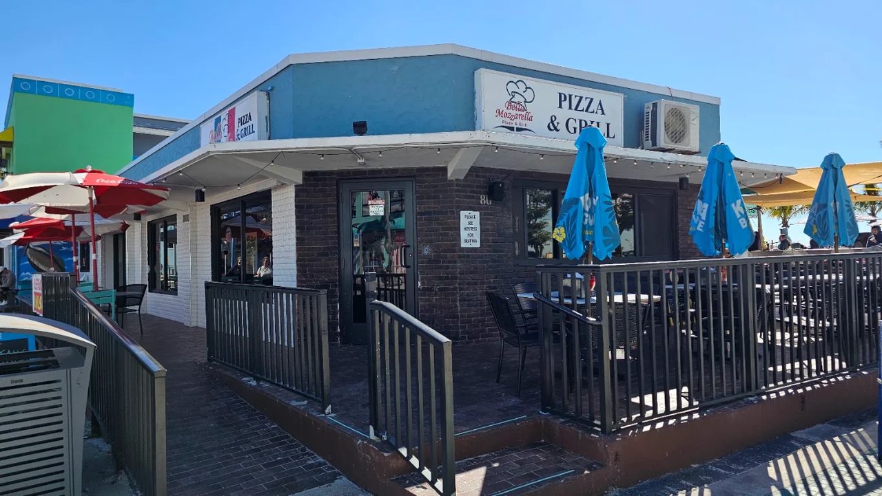 The Bella Mozzarella corner storefront on Old San Carlos Blvd, PIZZA & GRILL sign above the railed patio