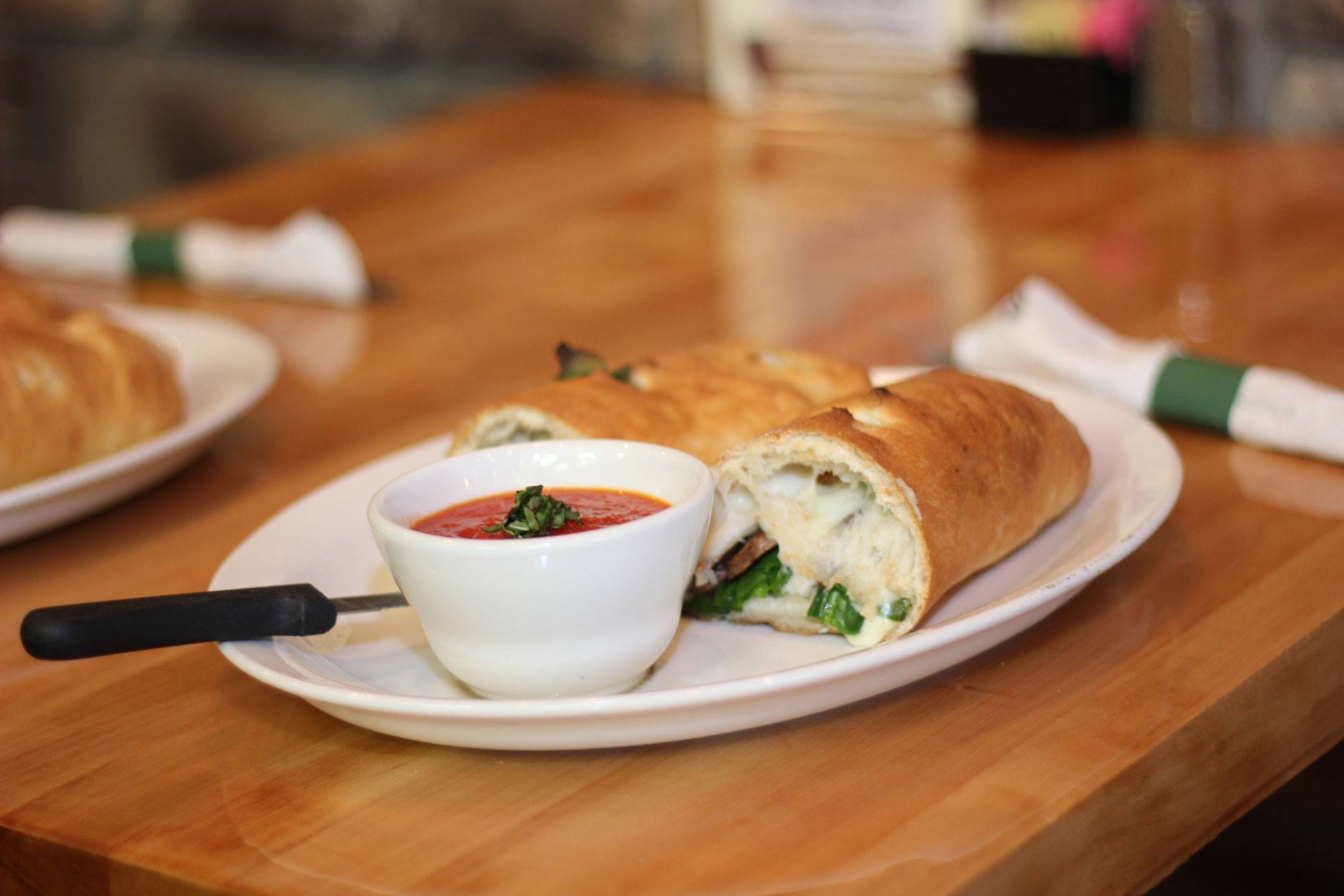 Golden-baked stromboli sliced open beside a cup of marinara